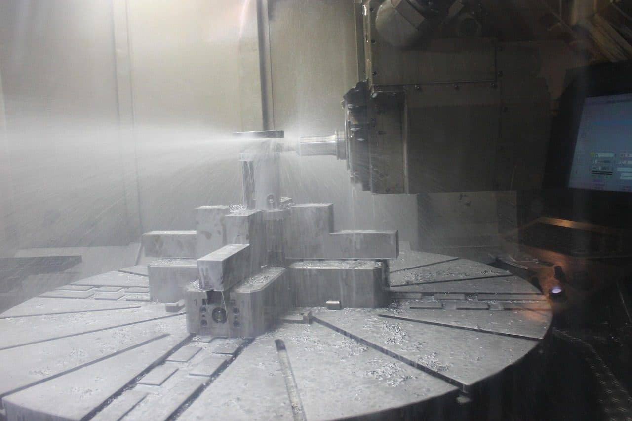 CNC machining centre milling steel blocks under coolant spray, a product line that needs a clear marketing plan