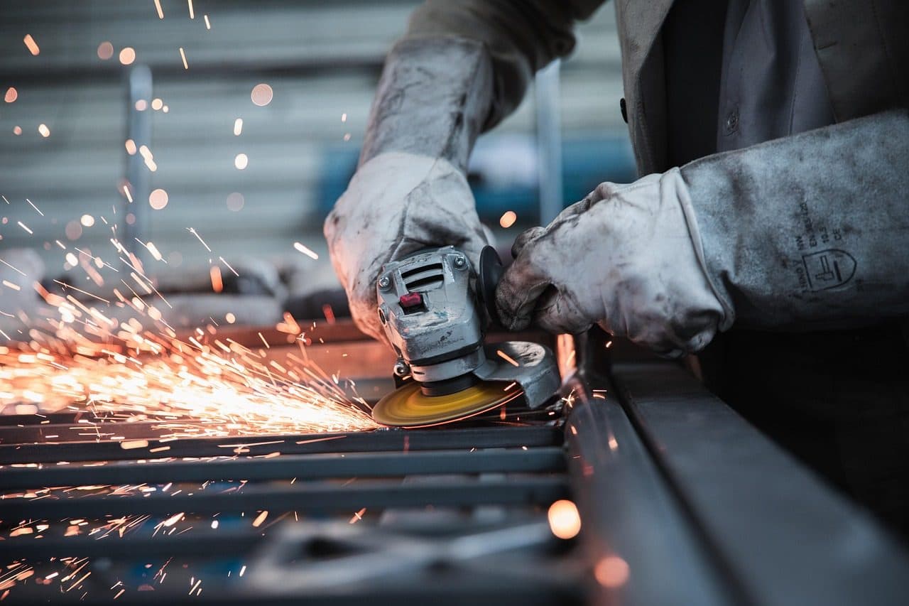 Metalworker grinding a steel part with sparks flying, the hands-on work digital marketing for manufacturers has to explain