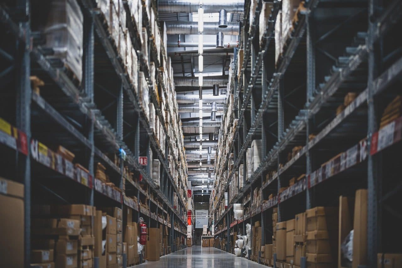 Long warehouse aisle with high shelves full of stock